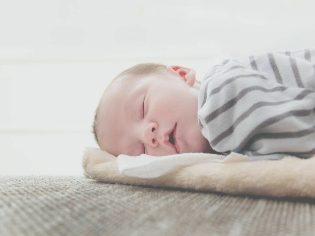 schlafendes Baby in Bauchlage mit gestreiftem Strampler