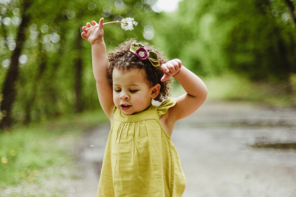 kleines Mädchen hüpft mit Sommerblume