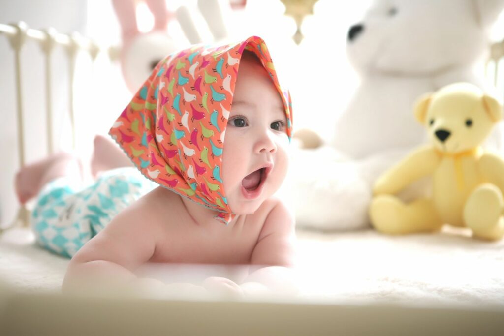 süßes Baby auf dem Bauch liegend mit hübschem Kopftuch 