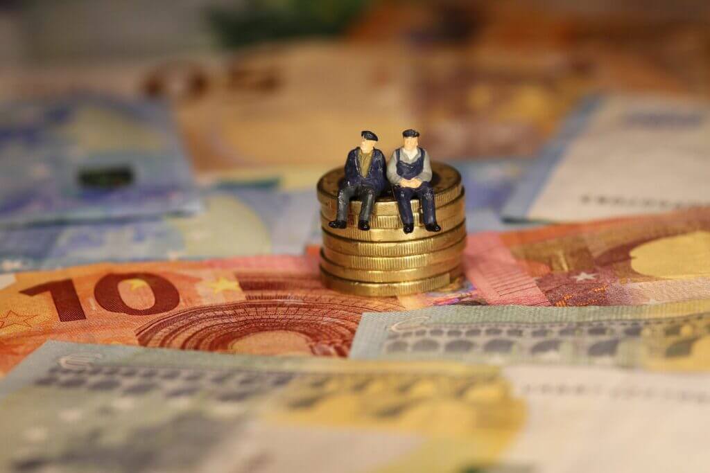 Rentnerfiguren sitzen auf Euromünzen