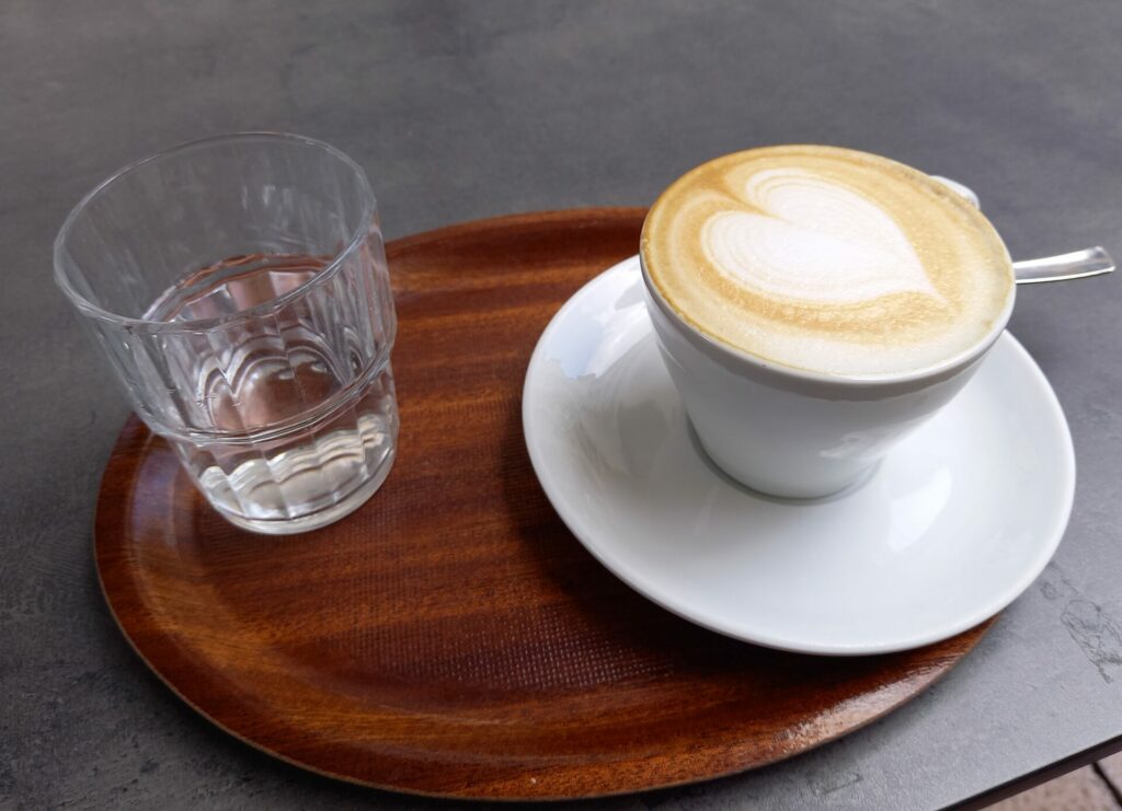 Cappuccino auf einem Tablett und ein Glas Wasser