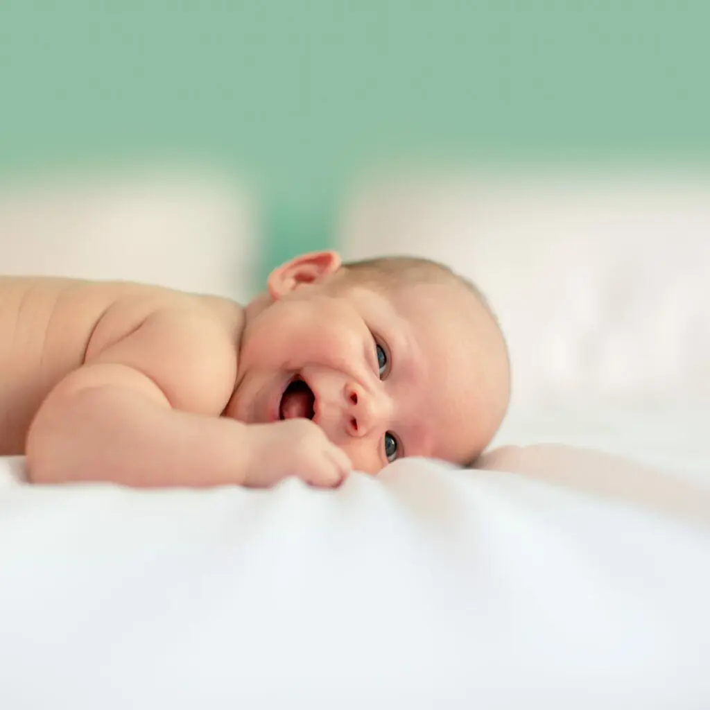 nackiges, lachendes Baby liegt auf dem Bauch