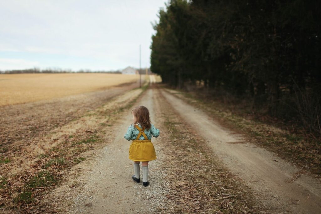 kleines Mädchen im gelben Rock auf einsamen Feldweg