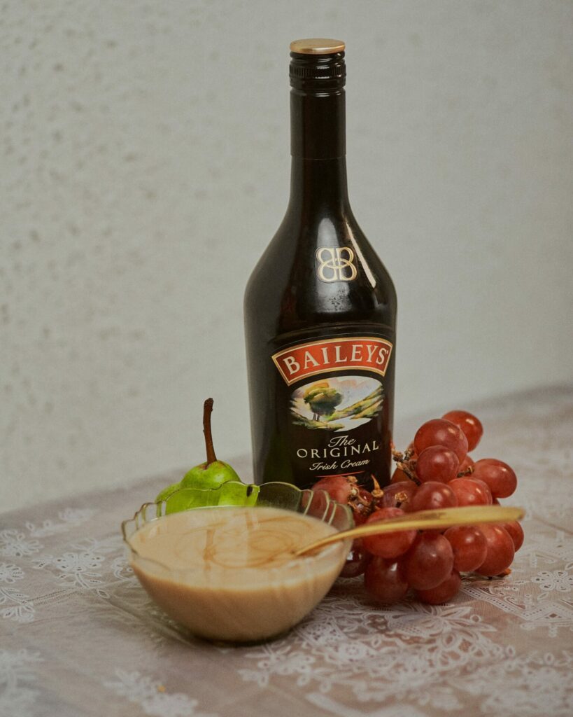 eine flasche Baileys, eine Schale Pudding mit Baileys und Obst