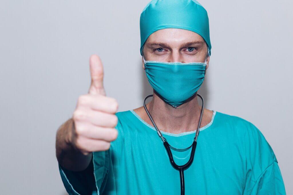 Arzt im OP-Anzug mit Mundschutz und Stestoskop