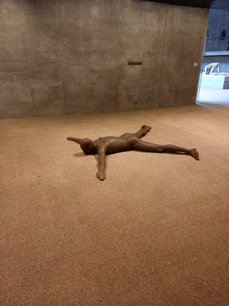Skulptur nackter mann am Boden